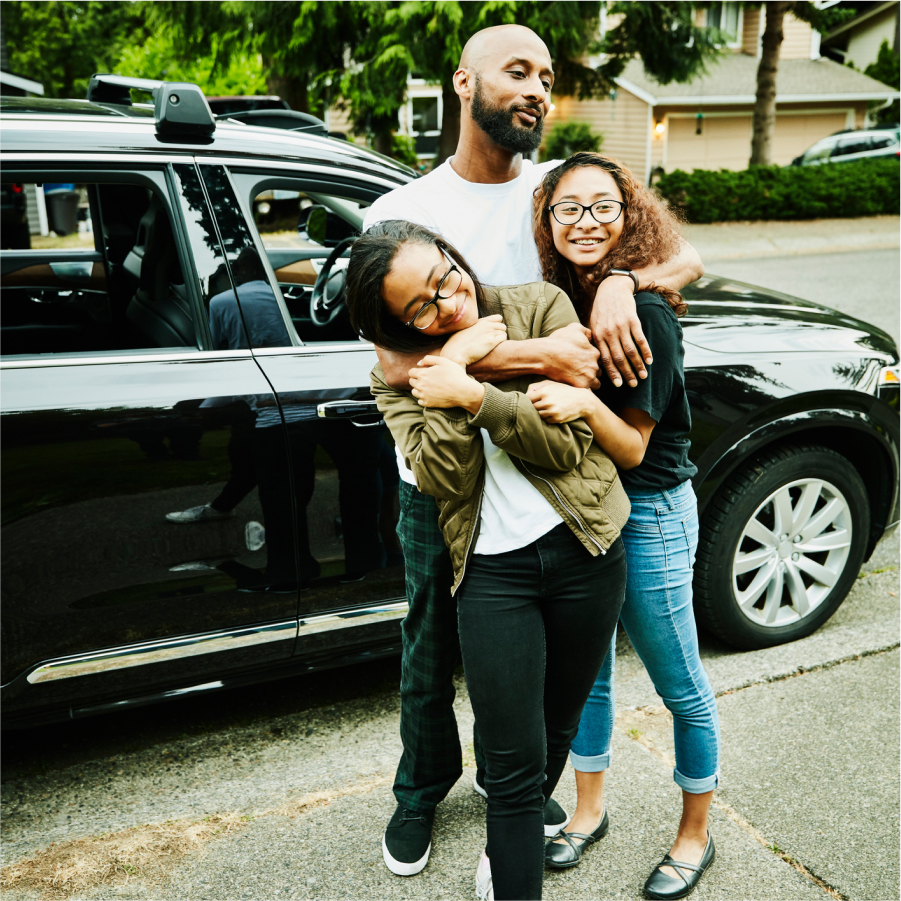 Happy family hugging in front of their clean car