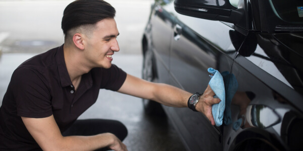 Smiling man polishing a car 